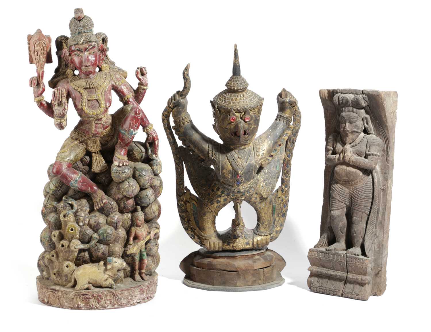 THREE EASTERN CARVINGS to include: a polychrome painted figure of Lakshmi sat on a pile of fruits, a