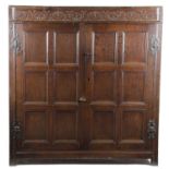 A PANELLED OAK CUPBOARD 17TH CENTURY with a scrolling frieze above a pair of doors, enclosing a
