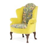 A GEORGE II WALNUT WING ARMCHAIR C.1730 with later floral needlework upholstery, on shell capped