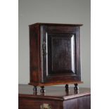 A GEORGE II OAK SPICE CUPBOARD DATED '1732' with a panelled door enclosing ten drawers, on