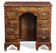 A GEORGE II WALNUT KNEEHOLE DESK C.1735 inlaid with stringing and crossbanding, the quarter veneered