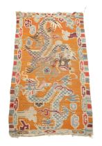 A TIBETAN RUG C.1920 the orange ground with two sparring dragons enclosed by narrow polychrome