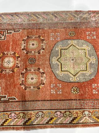 A KHOTAN RUG EAST TURKESTAN, C.1920 the pale terracotta field centred by a rondel framed by six - Image 4 of 5