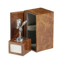 A ROLLS ROYCE SPIRIT OF ECSTASY PRESENTATION CAR MASCOT C.1971 on a burr walnut plinth, with a white