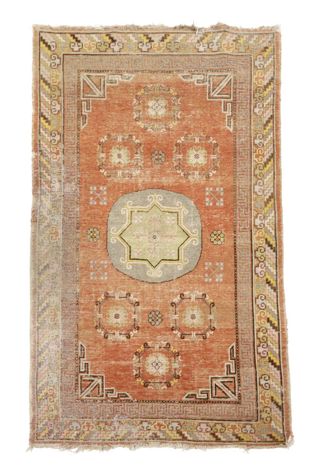 A KHOTAN RUG EAST TURKESTAN, C.1920 the pale terracotta field centred by a rondel framed by six