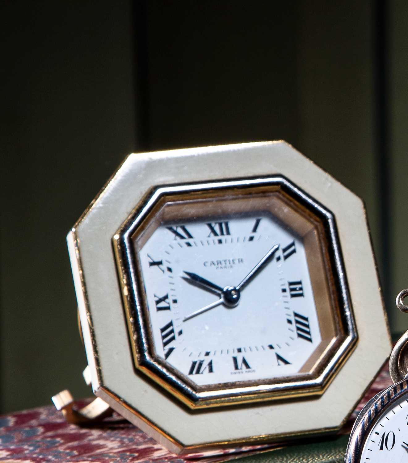 A TRAVEL CLOCK BY CARTIER the signed dial with black Roman numerals to an octagonal metal frame,