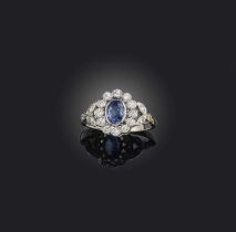 A sapphire and diamond cluster ring, the oval sapphire set within a surround of round brilliant-