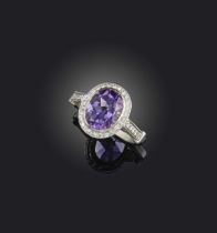An amethyst and diamond cluster ring, the oval amethyst set within a surround of circular-cut