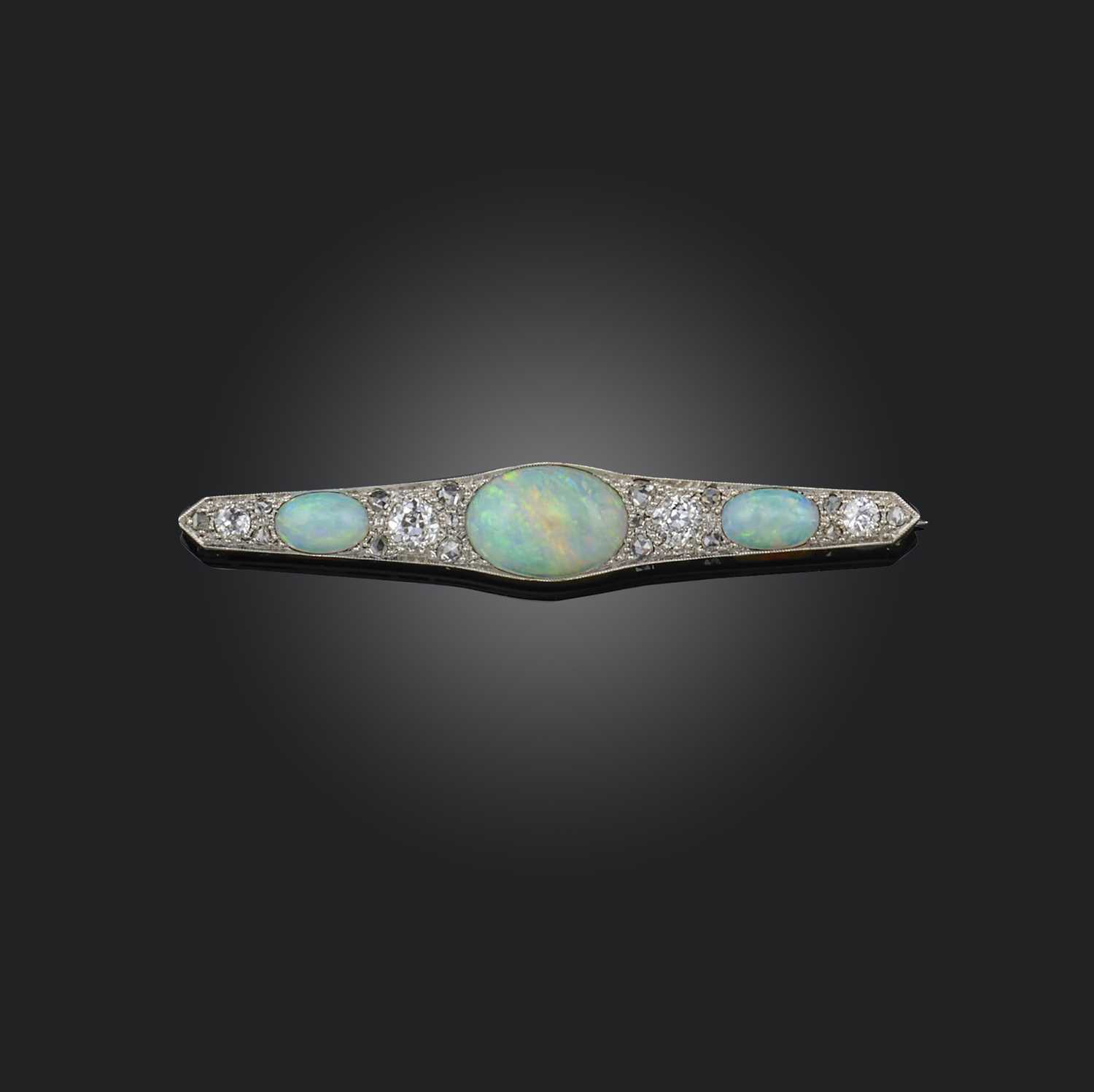 An opal and diamond brooch, early 20th century, of bar design, set with three cabochon opals, spaced