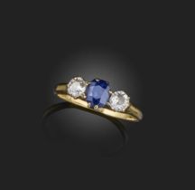 A sapphire and diamond three-stone ring, set with an oval-shaped sapphire flanked by circular-cut