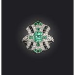 An emerald, onyx and diamond ring, designed in the Art Deco style, centring on a with a step-cut
