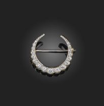 A diamond brooch, designed as a crescent moon, set with a line of graduated brilliant-cut