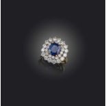 A sapphire and diamond cluster ring, set with a cushion-shaped sapphire within a concentric surround