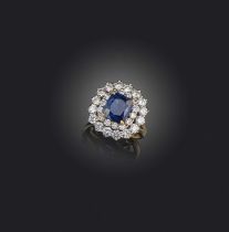 A sapphire and diamond cluster ring, set with a cushion-shaped sapphire within a concentric surround