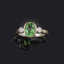 A tsavorite garnet and diamond ring, the oval green garnet flanked with round brilliant-cut diamonds