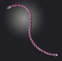 A ruby and diamond line bracelet, designed as a line of oval rubies totalling 9.61 carats, spaced