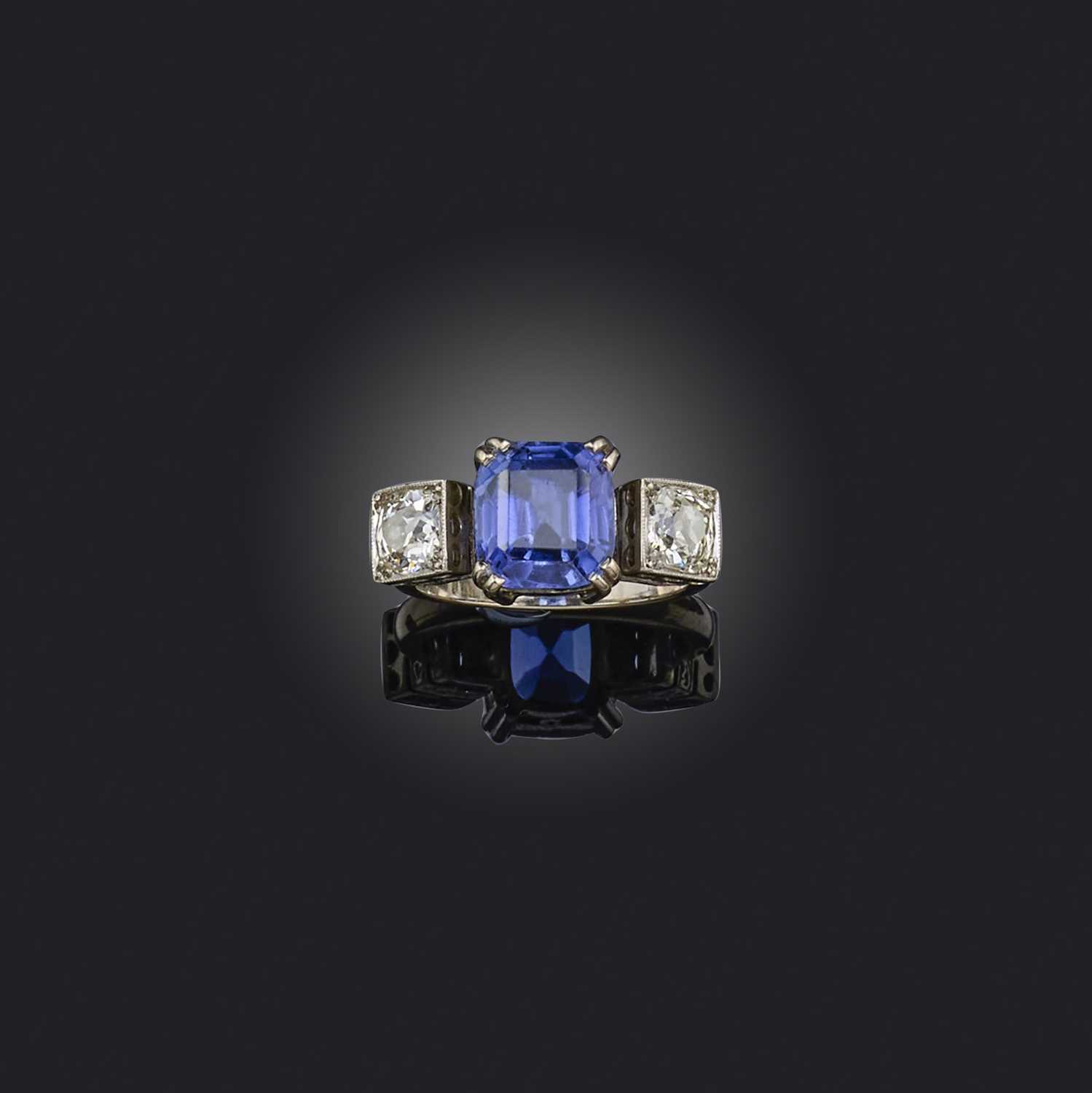 A tanzanite and diamond three stone ring, set with a cushion-shaped tanzanite flanked with old