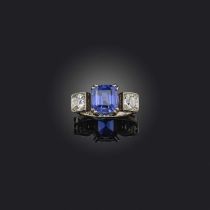 A tanzanite and diamond three stone ring, set with a cushion-shaped tanzanite flanked with old