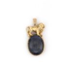 A sapphire pendant, set with a large cabochon sapphire, within a gold mount topped with a lion,