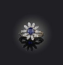 Birks, a sapphire and diamond ring, of cluster design, set with an oval sapphire within a border