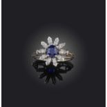 Birks, a sapphire and diamond ring, of cluster design, set with an oval sapphire within a border