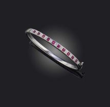 A ruby and diamond bangle, of hinged design, the front channel-set with a sequence of square