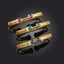 Vourakis, three gem-set gold bangles, set with ruby, emerald and sapphire cabochon terminals