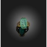 A carved emerald ring, set with an elongated octagonal emerald measuring 15.1 x 9.4 x 4.0mm, its