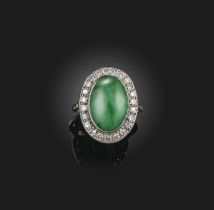 A jadeite and diamond cluster ring, the oval jade cabochon set within a surround of circular-cut