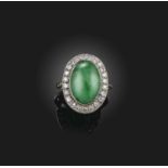 A jadeite and diamond cluster ring, the oval jade cabochon set within a surround of circular-cut