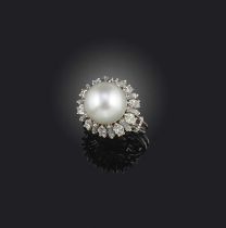 A cultured pearl and diamond ring, of cluster design, set with a cultured pearl within a border of