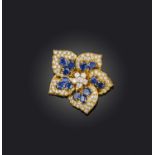 A sapphire and diamond flower brooch, set overall with oval-shaped sapphires within a surround of