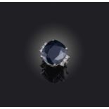 A black sapphire and diamond ring, the cushion-shaped sapphire flanked with three circular-cut