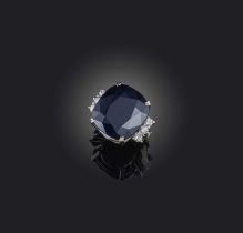 A black sapphire and diamond ring, the cushion-shaped sapphire flanked with three circular-cut