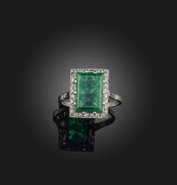 An emerald and diamond ring, early 20th century, claw-set with a step-cut emerald weighing