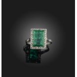 An emerald and diamond ring, early 20th century, claw-set with a step-cut emerald weighing