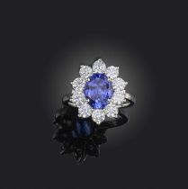 A tanzanite and diamond cluster ring, the oval tanzanite set within a surround of circular-cut