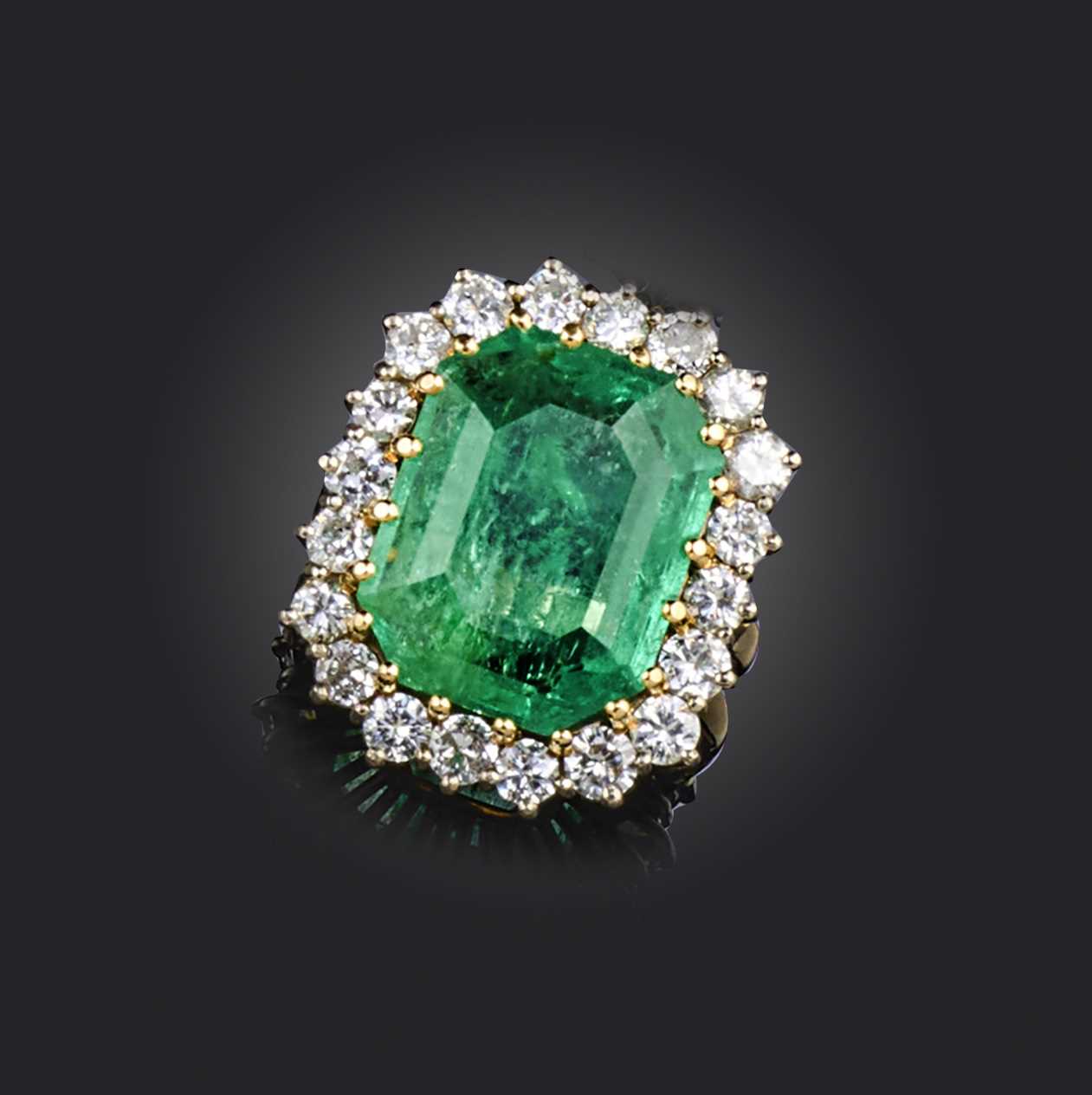 An emerald and diamond cluster ring, the emerald-cut emerald weighing approximately 9.00cts, set