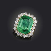 An emerald and diamond cluster ring, the emerald-cut emerald weighing approximately 9.00cts, set