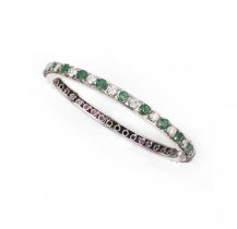 An emerald, ruby and diamond bangle, of hinged design, set to one side with circular-cut emeralds