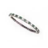 An emerald, ruby and diamond bangle, of hinged design, set to one side with circular-cut emeralds