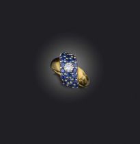 A sapphire and diamond ring, centring on a scroll motif pavé-set with circular-cut sapphires and a