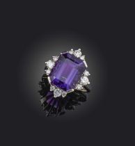 An amethyst and diamond cluster ring, the step-cut amethyst set within quatrefoil border of