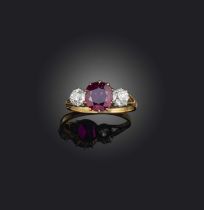 A ruby and diamond three-stone ring, late 19th century, the cushion-shaped ruby flanked by a pair of