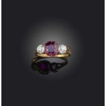 A ruby and diamond three-stone ring, late 19th century, the cushion-shaped ruby flanked by a pair of