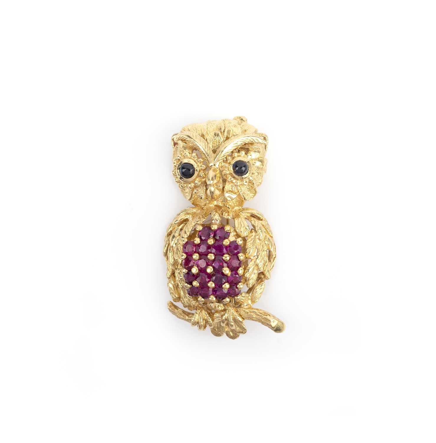 A gold, ruby and sapphire brooch, 1960s, in textured gold with circular cut rubies and cabochon