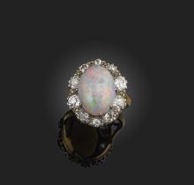 An opal and diamond ring, of cluster design, set with a cabochon opal within a border of circular-