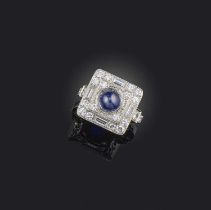 A sapphire and diamond ring, of square outline, set with a cabochon sapphire within a border of