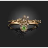 A demantoid garnet and diamond bangle, late 19th century, centring on a floral spray set with a