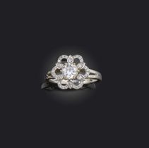 A diamond ring, designed as a floral cluster, centring on a circular-cut diamond weighing